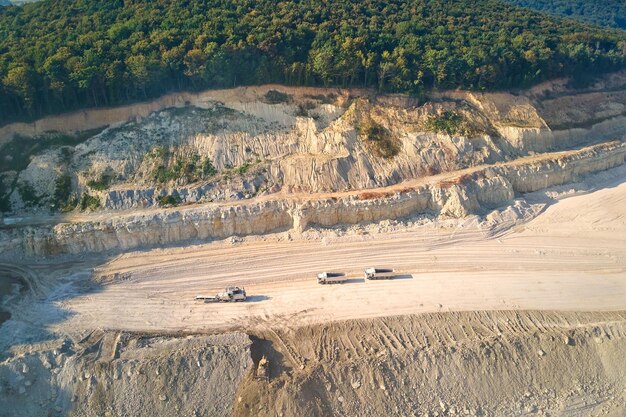 Veduta aerea dell'estrazione a cielo aperto di materiali calcarei per l'industria edile con escavatori e autocarri con cassone ribaltabile