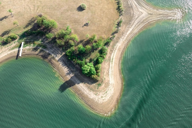 Veduta aerea dell'isola con alberi verdi e strade circondate dal mare o dall'oceano con acqua limpida