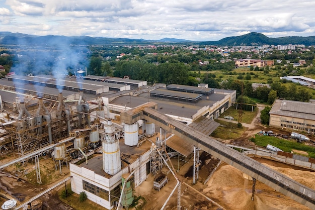 Veduta aerea della fabbrica di lavorazione del legno con fumo proveniente dall'atmosfera inquinante del processo di produzione nel cantiere di produzione dell'impianto