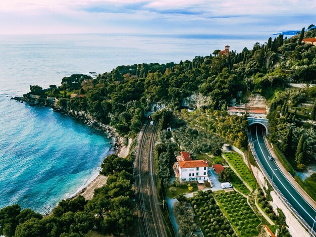 Veduta aerea della strada con auto e una piccola città italiana su una montagna dal mare turchese