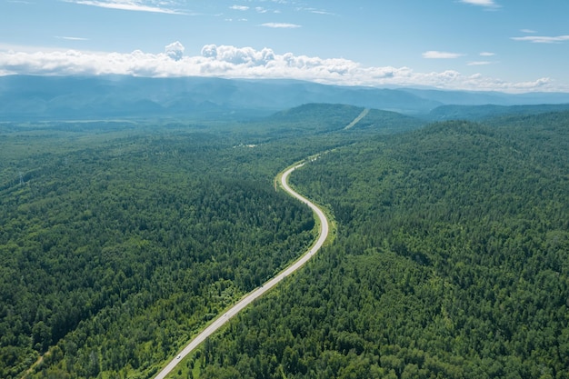 Veduta aerea della strada del lago Baikal. Una strada che attraversa un bosco di conifere, fotografia aerea da un drone. Strada tortuosa nell'ecoregione della taiga siberiana occidentale