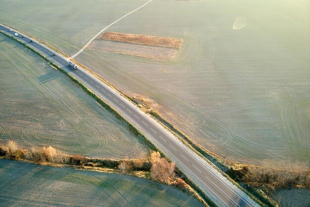 Veduta aerea della strada interurbana con auto a guida veloce al tramonto Vista dall'alto dal drone del traffico autostradale in serata