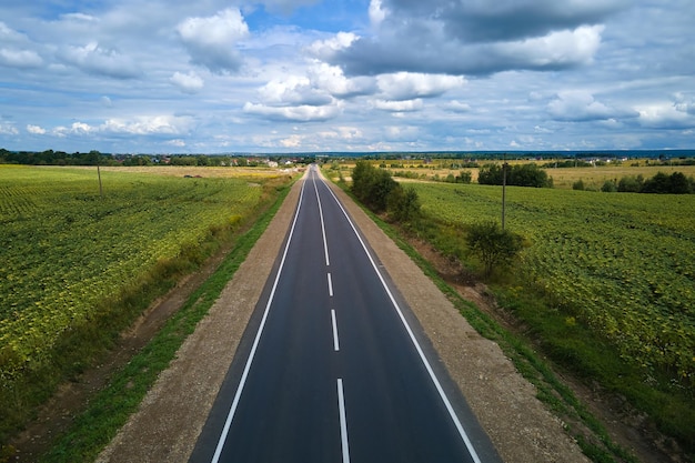 Veduta aerea della strada interurbana vuota tra i verdi campi agricoli Vista dall'alto dal drone della carreggiata autostradale