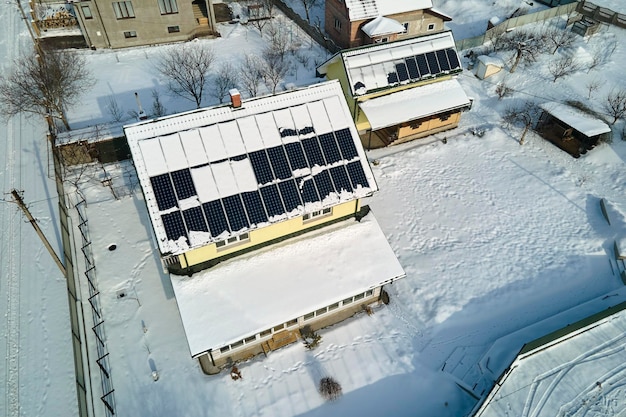 Veduta aerea dello scioglimento della neve dai pannelli solari fotovoltaici coperti installati sul tetto della casa per la produzione di energia elettrica pulita Bassa efficacia dell'elettricità rinnovabile nell'inverno della regione settentrionale