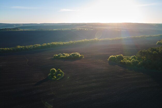 Veduta aerea di campi agricoli arati con terreno fertile coltivato preparato per piantare colture tra boschi verdi in primavera