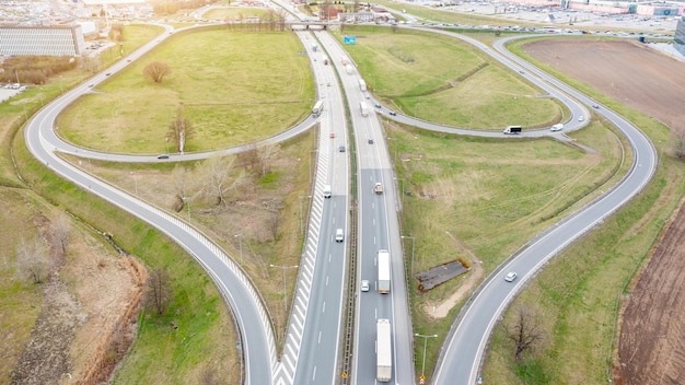 Veduta aerea di un'autostrada con svincoli molti camion stanno guidando sulle catene stradali logistiche di interscambio di trasporto stradale