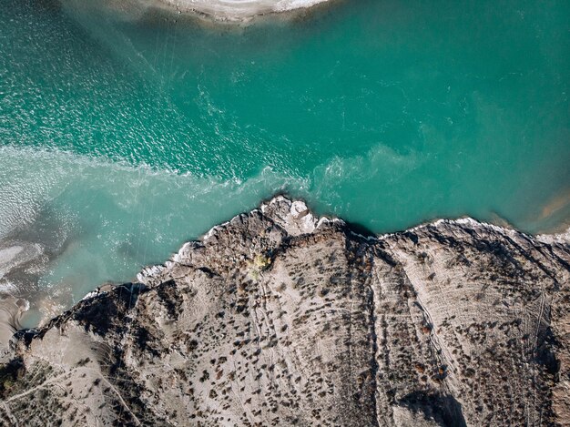 Veduta aerea di un lungo fiume turchese chiaro che si estende lungo gli argini sabbiosi, dividendosi in due direzioni alla fine del fiume