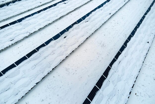 Veduta aerea di una centrale elettrica sostenibile coperta di neve con file di pannelli fotovoltaici solari per la produzione di energia elettrica pulita Bassa efficacia dell'elettricità rinnovabile nell'inverno settentrionale