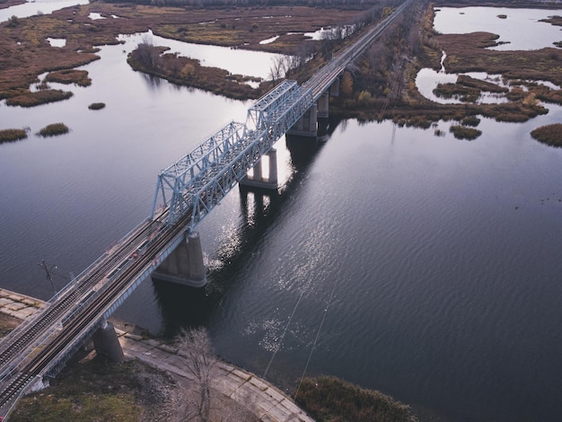 Veduta aerea di uno specchio d'acqua con un ponte ferroviario in metallo su una base in cemento.