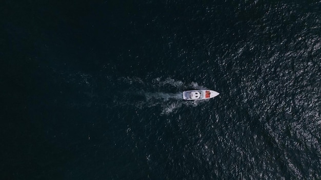 Veduta aerea tramite drone di un'imbarcazione da diporto che corre tra le onde del mare creando un'immagine affascinante di velocità e libertà
