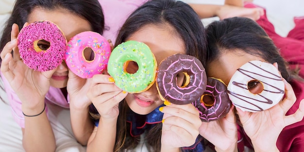 Veduta dall'alto delle ragazze che coprono gli occhi con le ciambelle