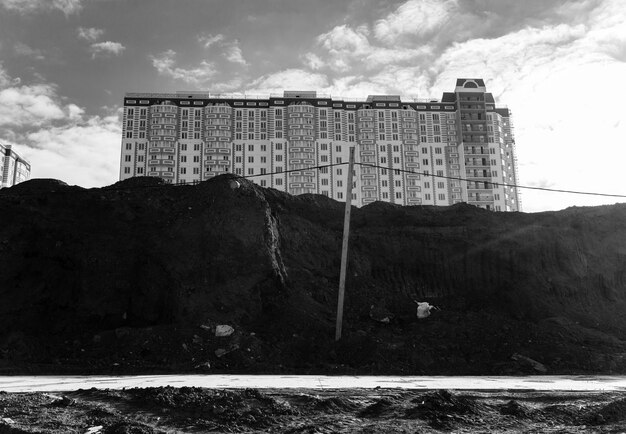 Veduta del nuovo edificio residenziale multipiano, posto ai margini del cantiere. Foto in bianco e nero.