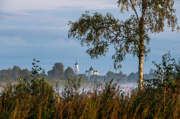 Veduta della chiesa dall'altra parte del fiume in una nebbiosa mattina all'alba.