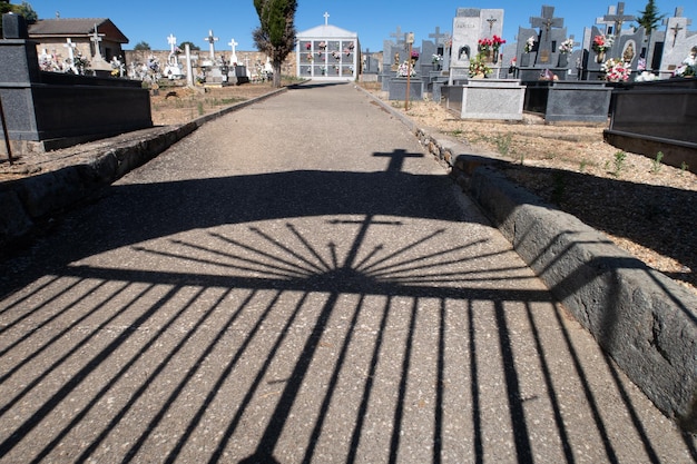 Veduta di un cimitero cristiano con l'ombra del recinto e della croce a terra