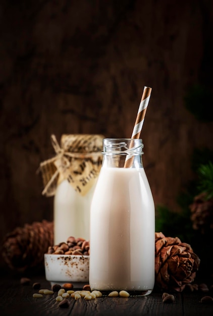 Vegano Latte di noce di cedro in bottiglie closeup tavola di legno sfondo Latte alternativo non caseario Cibo vegetariano sano e concetto di bevande Copia spazio