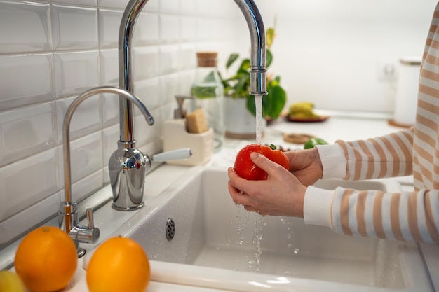 Vegetali freschi peperoncino rosso lavaggio a mano in cucina domestica cibo grezzo vegetariano sano