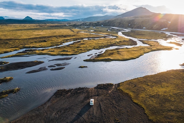 Veicolo a quattro ruote motrici parcheggiato vicino al grande fiume che attraversa la sera su remote zone rurali degli altopiani islandesi