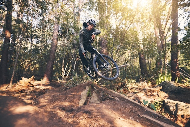 Velocità di trucco in bicicletta e uomo su una bicicletta su una strada forestale sterrata facendo allenamento ed esercizio su una bicicletta Percorso veloce all'aperto e atleta motociclista con cardio ed energia in un'avventura in bicicletta con salto