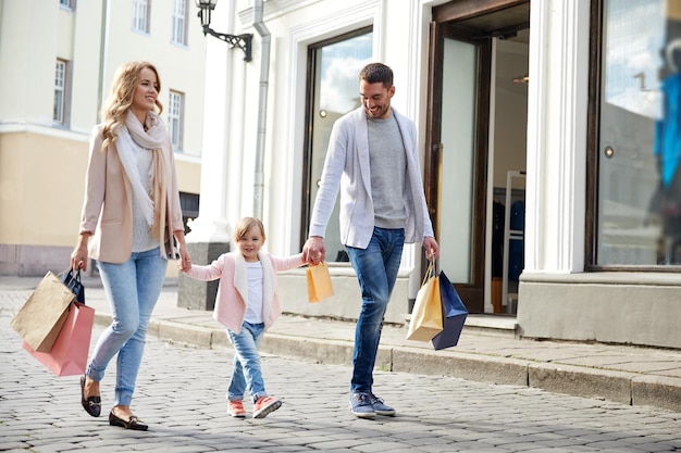vendita, consumismo e concetto di persone - famiglia felice con bambino e borse della spesa in città