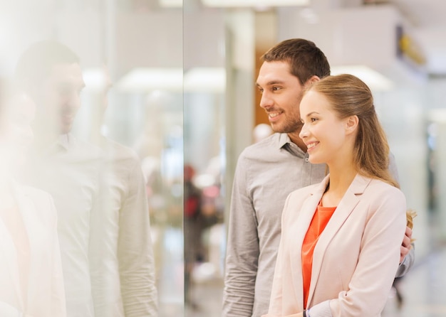 vendita, consumismo e concetto di persone - giovani coppie felici che cercano di vetrine nel centro commerciale