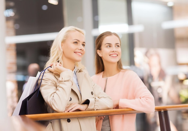 vendita, consumismo e concetto di persone - giovani donne felici con borse della spesa nel centro commerciale