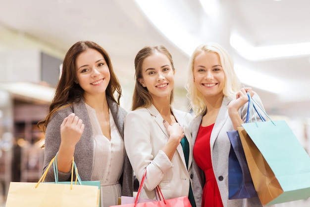 vendita, consumismo e concetto di persone - giovani donne felici con borse della spesa nel centro commerciale