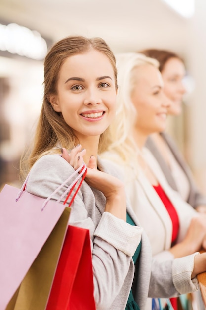 vendita, consumismo e concetto di persone - giovani donne felici con borse della spesa nel centro commerciale