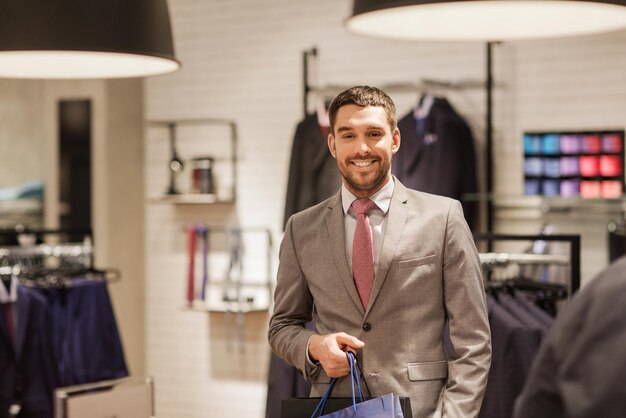 vendita, moda, vendita al dettaglio, stile aziendale e concetto di persone - uomo felice con le borse della spesa al negozio di abbigliamento