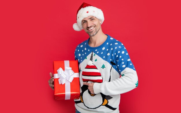Vendita regalo per Natale felice uomo caucasico che punta il dito sul regalo di Natale isolato su rosso