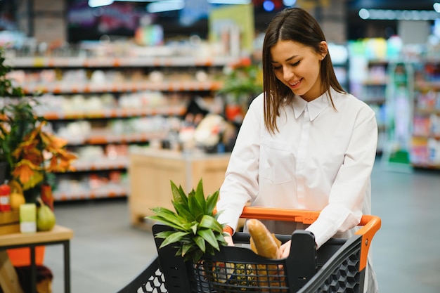 Vendita, shopping, consumismo e concetto di persone - donna con cesto di cibo al negozio di alimentari o al supermercato