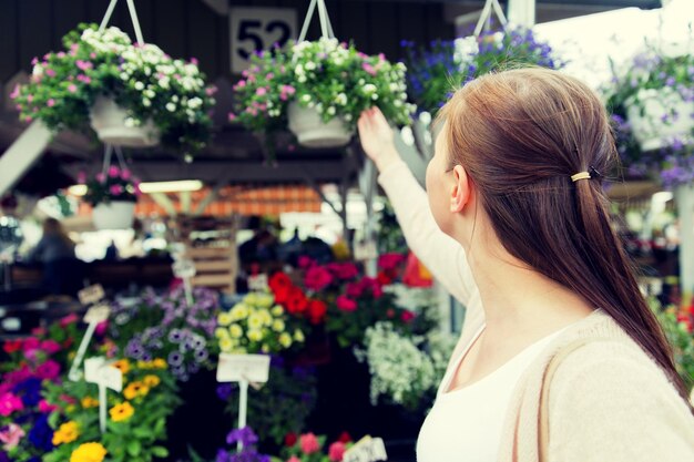 vendita, shopping, giardinaggio e concetto di persone - primo piano di donna che sceglie fiori al mercato di strada