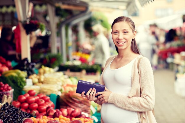 vendita, shopping, gravidanza e concetto di persone - donna incinta felice con portafoglio e soldi che comprano cibo al mercato di strada