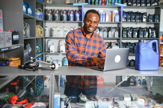 Venditore africano sorridente, negozio di ricambi auto.