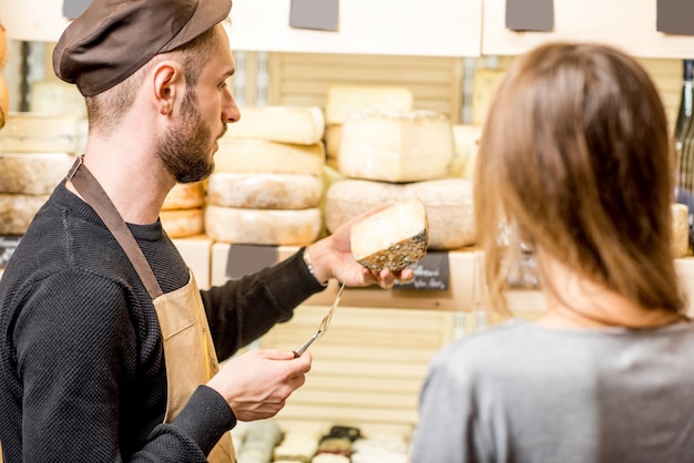 Venditore con una cliente donna che sceglie un formaggio per l'acquisto al negozio di alimentari
