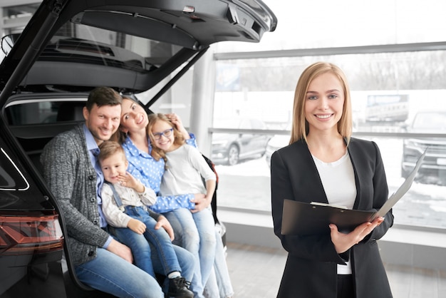 Venditore dell'automobile che esamina macchina fotografica e che posa nello showroom automatico