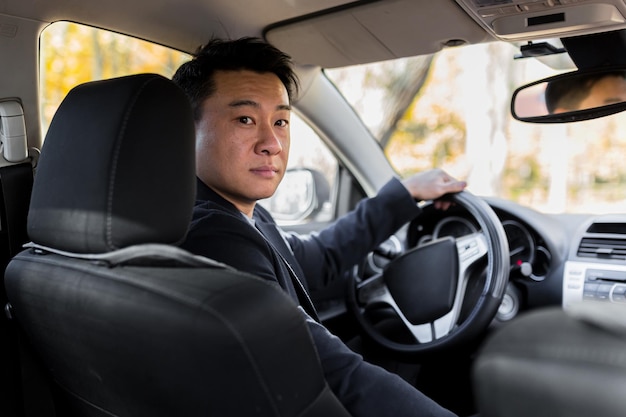 Venditore di auto di successo uomo d'affari Autista asiatico maschio al volante guardando nella telecamera e sorridente