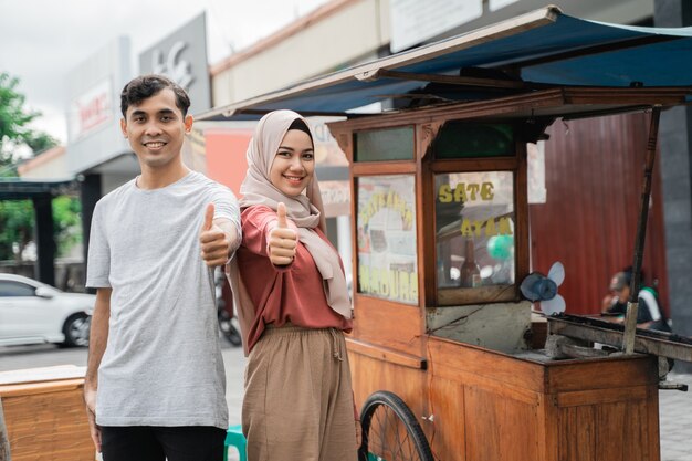 Venditore di cibo di strada con stallo a piedi di pollo indonesiano satay che cucina su una griglia a carbone caldo