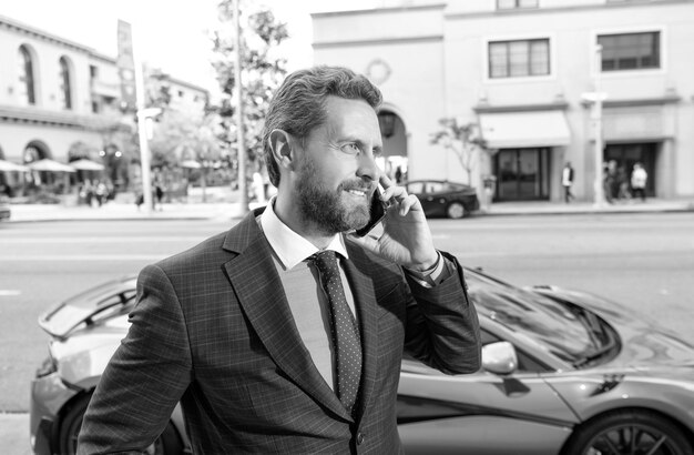 Venditore di successo che parla sul telefono cellulare ragazzo ricco auto a noleggio