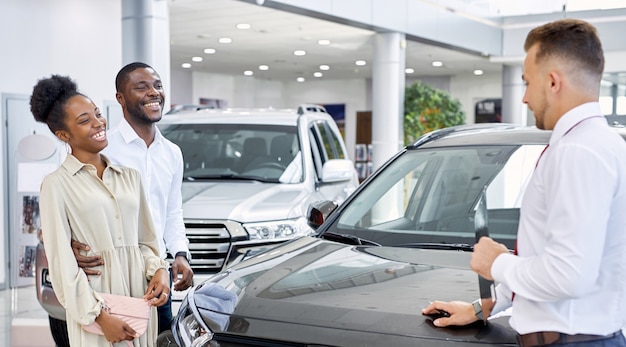 Venditore fiducioso uomo caucasico che vende auto presso concessionaria auto