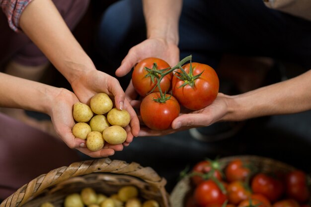 Venditori dell'uomo e della donna che tengono i pomodori e le patate alla drogheria