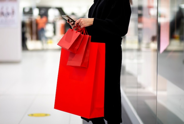 Venerdì nero, donna che tiene la borsa della spesa rossa sullo sfondo del centro commerciale