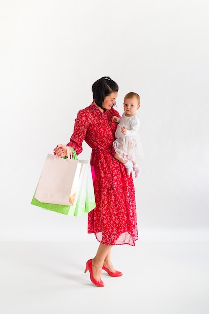 Venerdì nero. La donna sta tenendo i pacchetti. Mamma e bambino stanno facendo la spesa. Sfondo bianco.