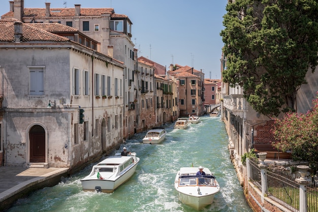 Venezia, Italia - 1° luglio 2018: Vista panoramica del canale stretto di Venezia con traffico di barche e edifici storici dal ponte Foscari. Paesaggio di giornata di sole estivo e cielo blu