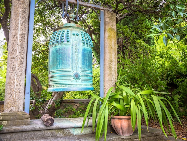 VENTIMIGLIA, ITALIA - CIRCA AGOSTO 2020: Antica campana giapponese situata nei giardini Hambury e finemente lavorata in bronzo. Sembra provenire da un santuario buddista distrutto da un incendio nel Giappone centrale.