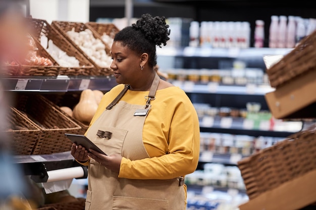 Vera donna di colore che lavora nel supermercato e indossa il grembiule