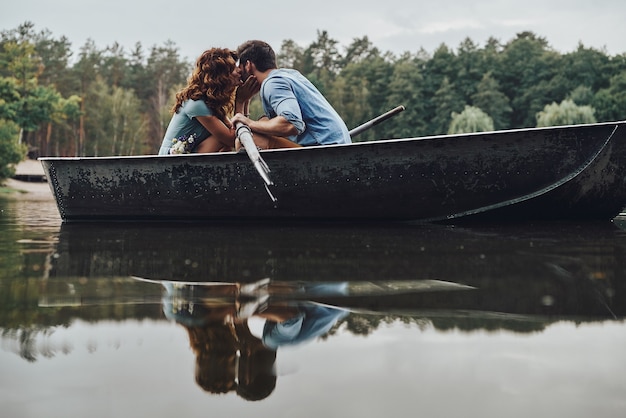 Vera passione. Bella giovane coppia che si bacia mentre rema su una barca durante un appuntamento romantico