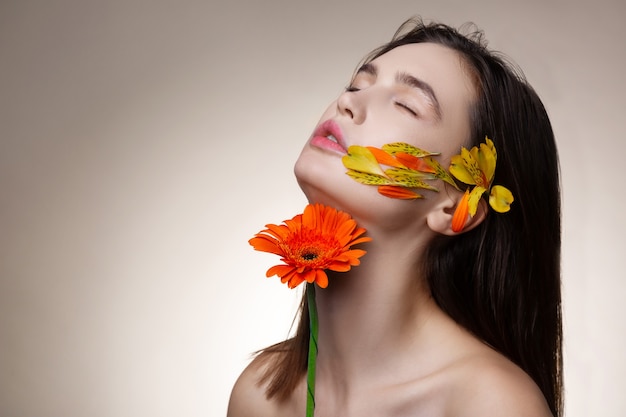 Vera soddisfazione. Modello magro dai capelli scuri che ottiene vera soddisfazione mentre posa con i fiori