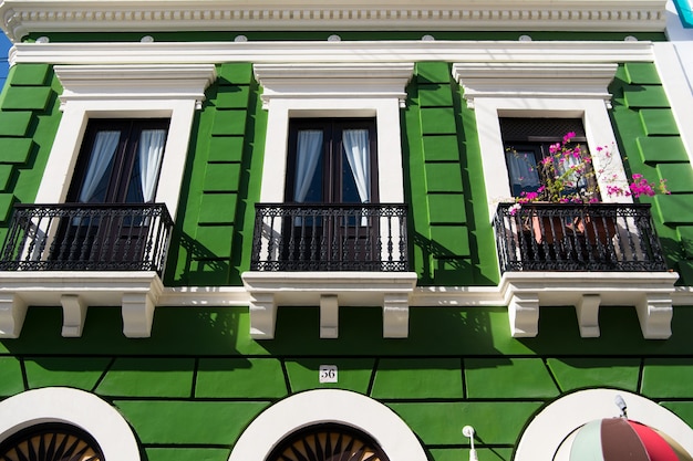 Verde edificio residenziale casa con recinzione di balcone in ferro nero e porte con finestre giornata di sole