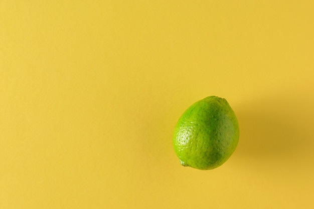 Verde lime su grande fondo giallo. Agrumi per fare un drink. Disposizione piatta.