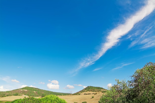 Verdi colline e cielo azzurro con nuvole in una giornata di sole ad Alghero in Sardegna